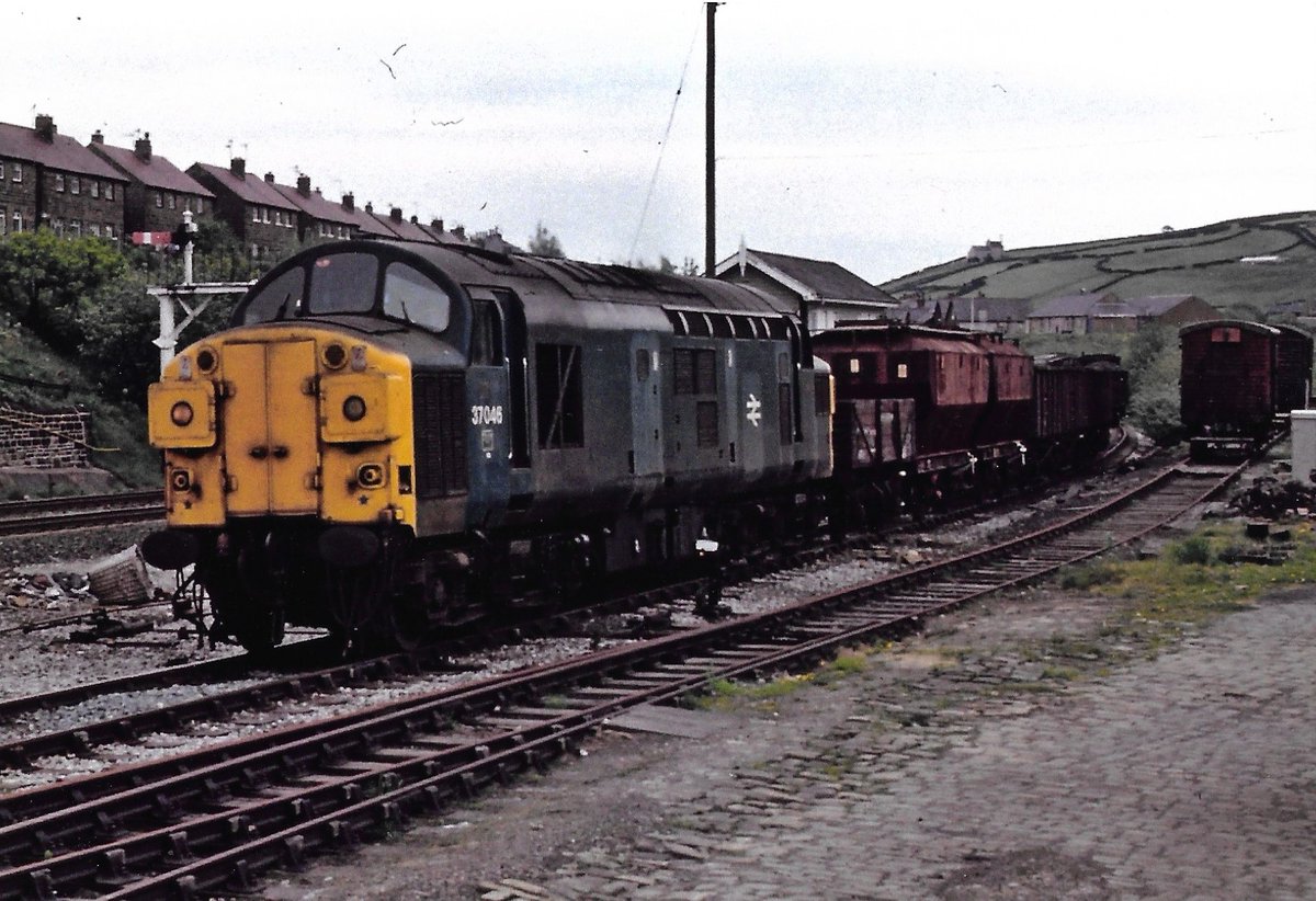 Held in the loop at Marsden, British Rail Class 37 diesel loco 37046 working a Vacuum Braked mixed freight of a 13 Ton High, Covhops & 16 Ton Mineral Wagons 17/5/82. Two Ventilated Vans in the siding. #Railfreight #BritishRail #Marsden #Class37 #trainspotting #wagons #BRBlue 🤓