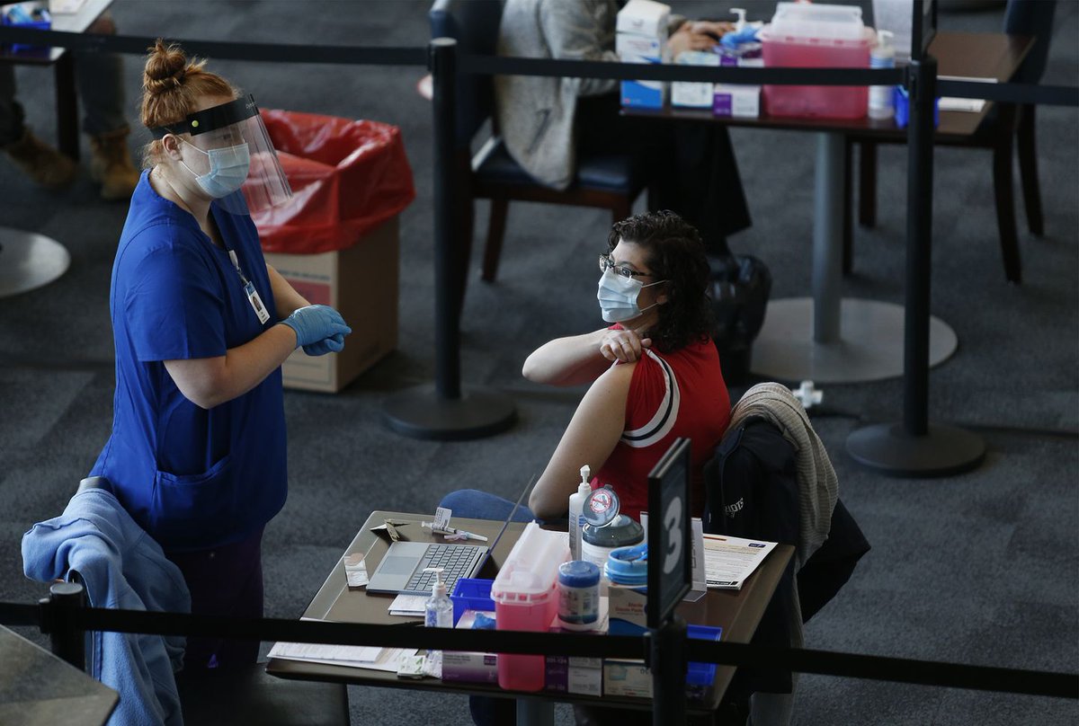 A picture of a nurse practitioner rolling up her sleeve and preparing to get a COVID-19 vaccine. 