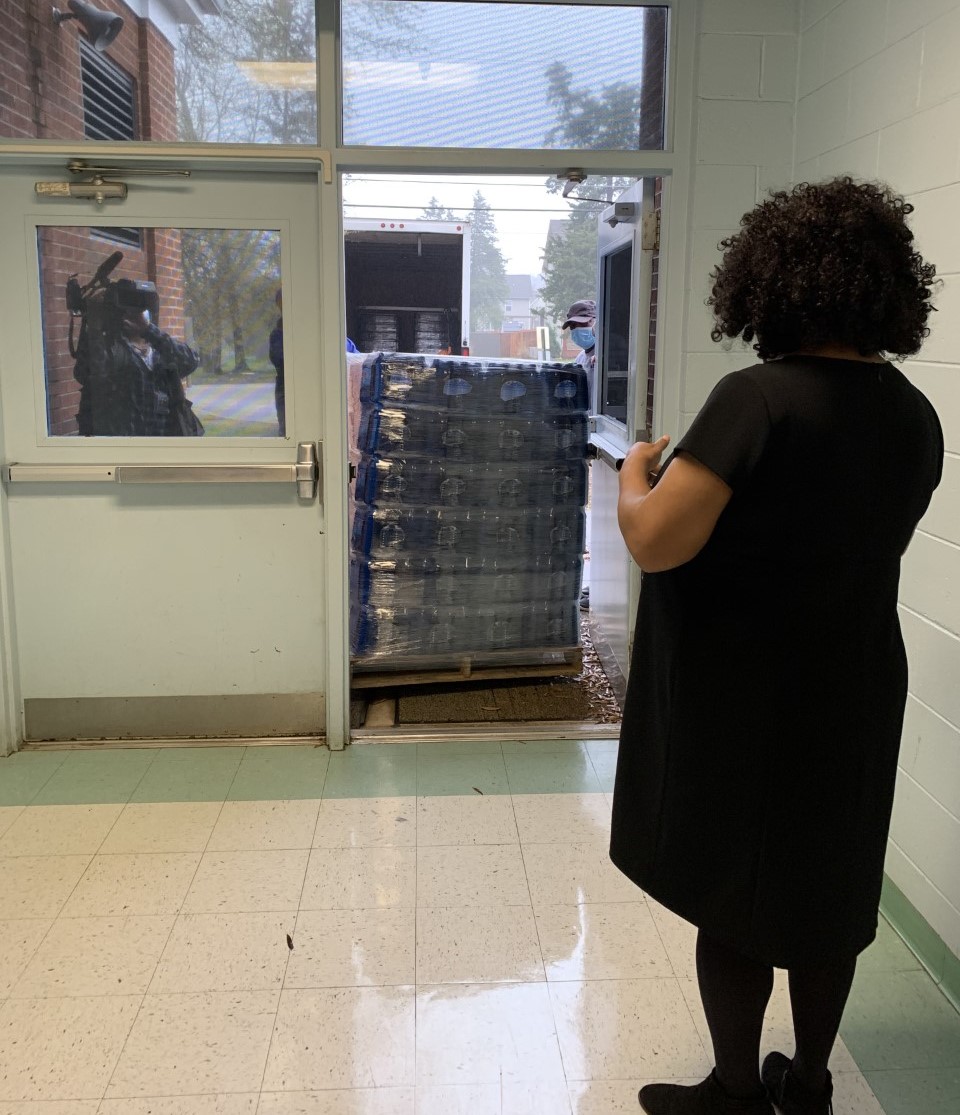Principal Valerie Brown watches as thousands of donated bottles of water are delivered to Bess T. Shepherd Elementary. Allied Eye helped coordinate this donation from Lipsey Water to help keep students hydrated while water fountains remain closed due to to the pandemic.