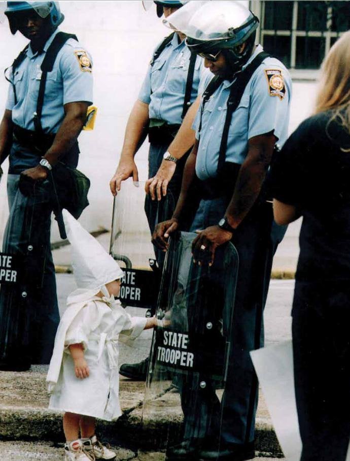 No one is born racist .State Trooper Allen Campbell and a small child in a KKK outfit during a Klan rally in Gainesville, 1992.Photo Todd Robertson."Me and this kid, neither one, made a choice to be here. The state patrol made me come, and his mom and dad brought him.”