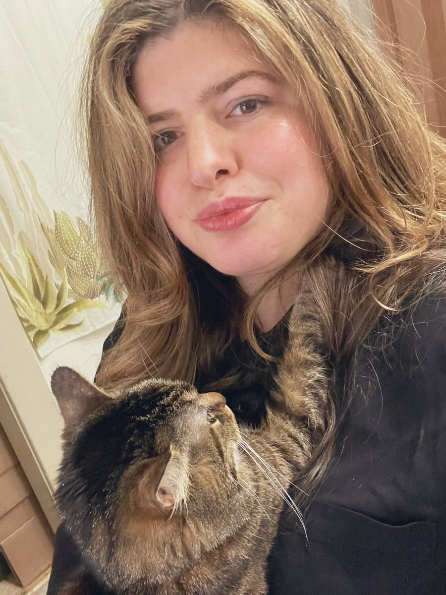 A tabby cat sits against its owner’s chest, its right paw outstretched over the owner’s neck.