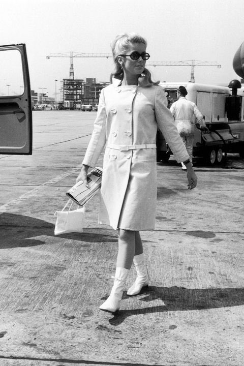 Catherine Deneuve wearing an overcoat and sunglases