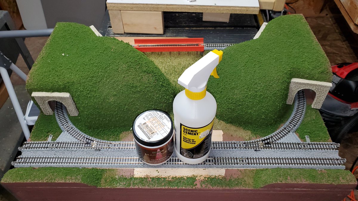 Attached the track with screws at the ends, glued the tunnel portals onto the mountains, and added ballast between the two tracks. I used the paint and spray bottle to help hold the track in place while the ballast glue dried. #KATOttrakprogress