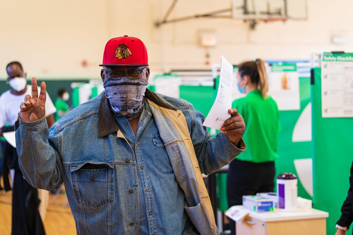 A man holds up his vaccination paperwork and makes a peace sign.