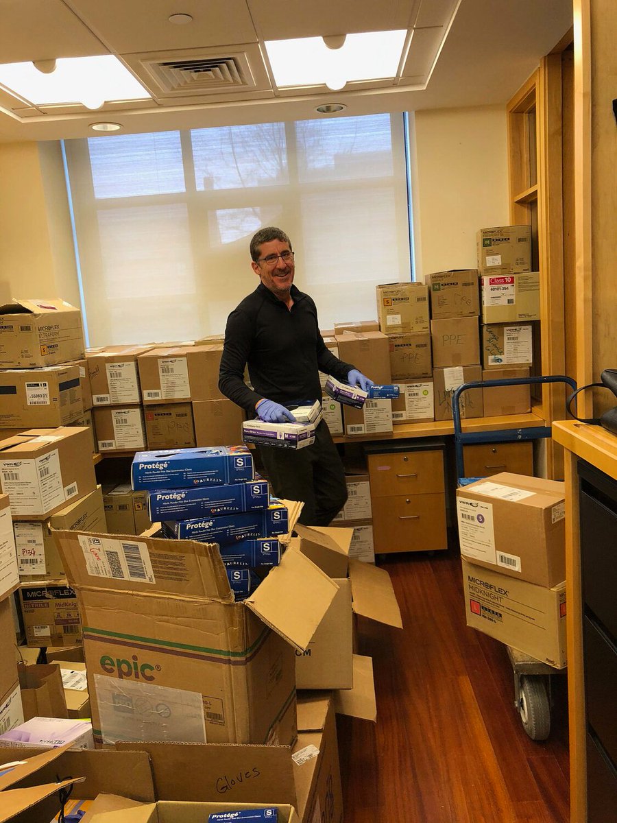 A man, surrounded by boxes, sorts PPE donations