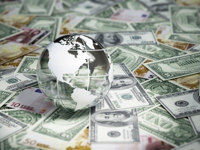 A glass globe rests on domestic and foreign currency.