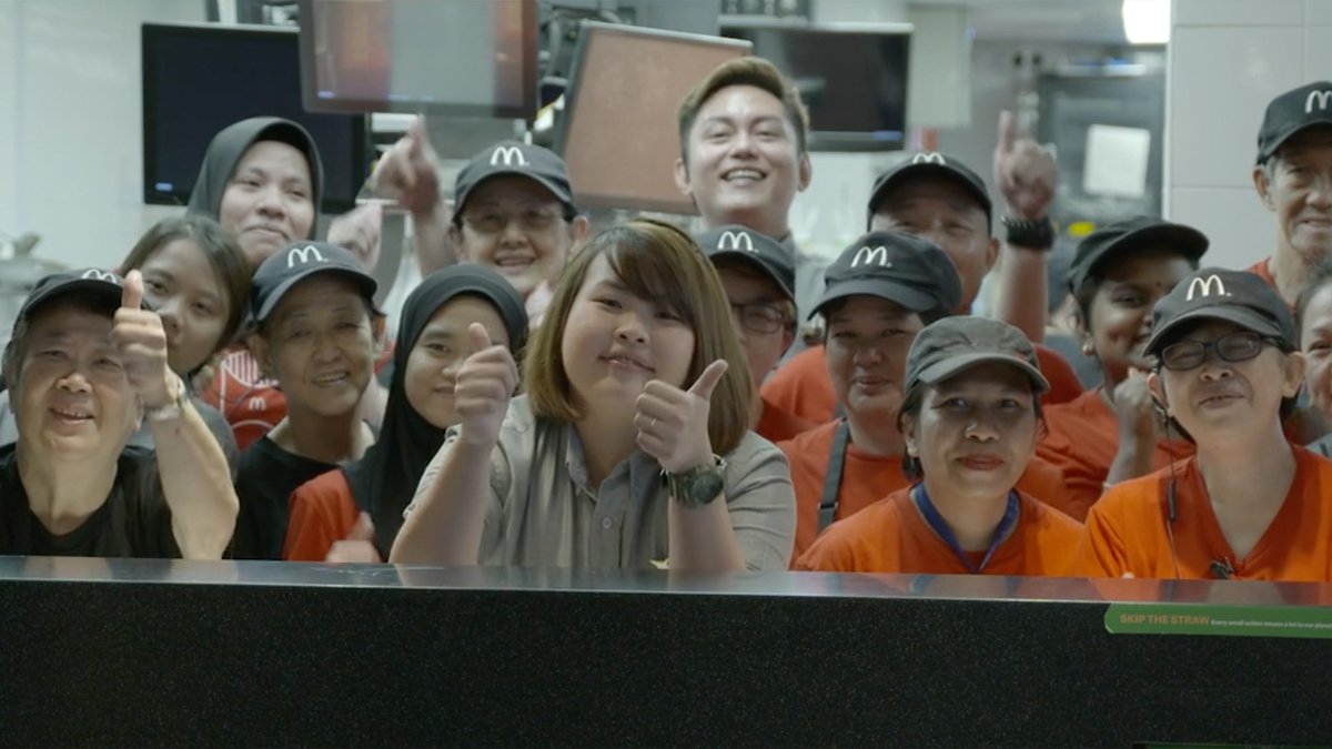 April giving two thumbs up surrounded by restaurant crew.