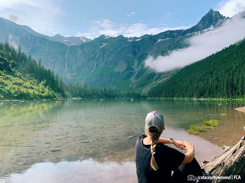 A traveler sitting in front of a beautiful lake in Glacier National Park.