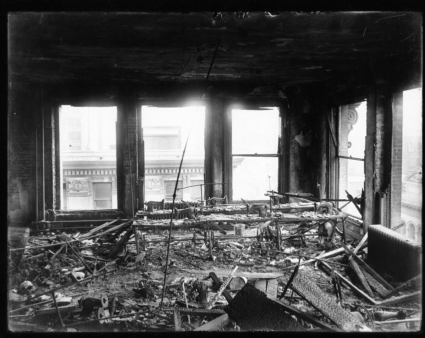 View of one of the working floors of the Triangle Shirtwaist Factory after the fire. Sewing machines and other metal items such as tables and shelves can be seen among the charred remains of other equipment. 