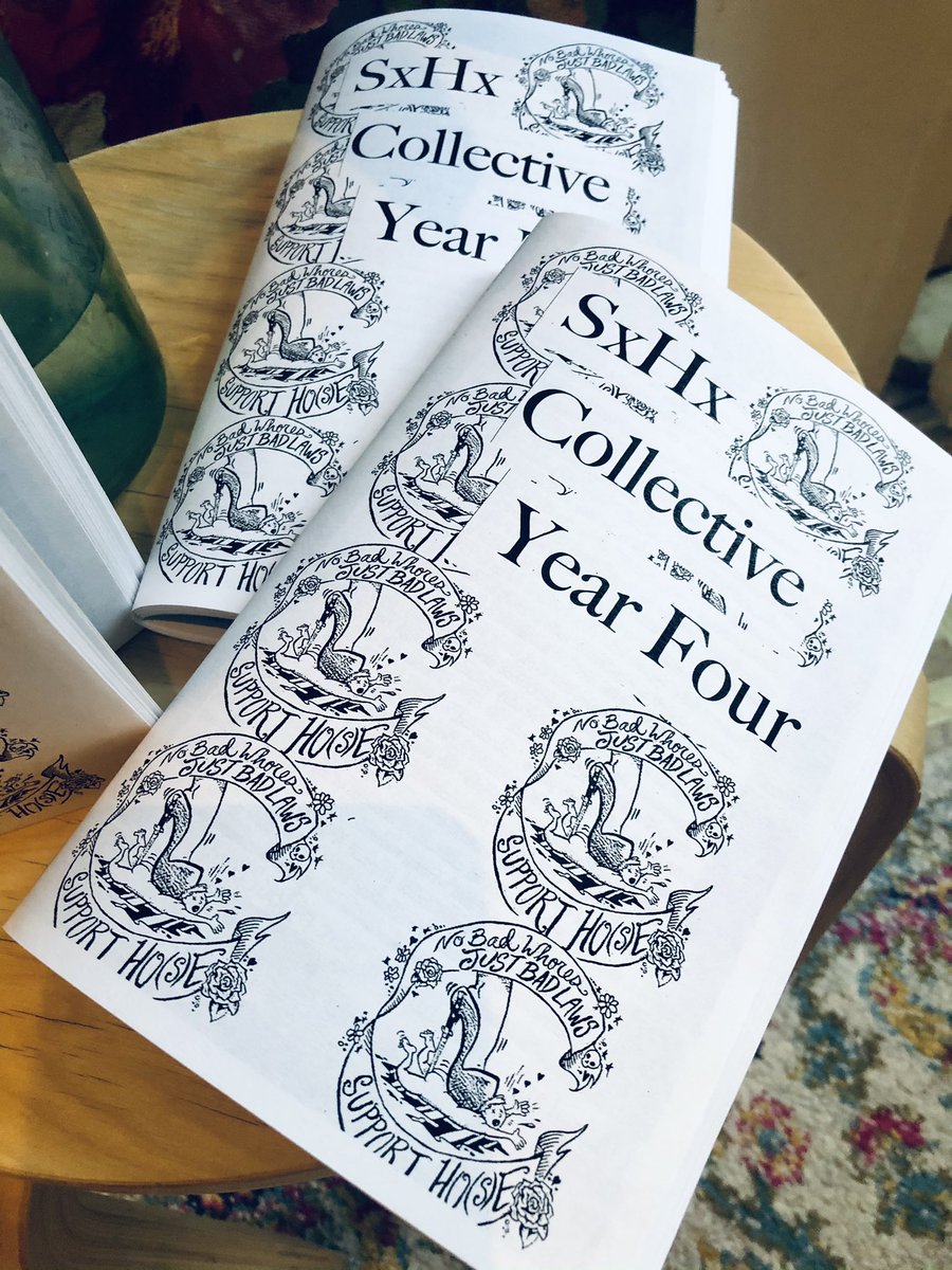 A color photo of a close up of the black and white zine covers, overlapping and displayed on a wooden stool, there’s a floral rug underneath the stool.