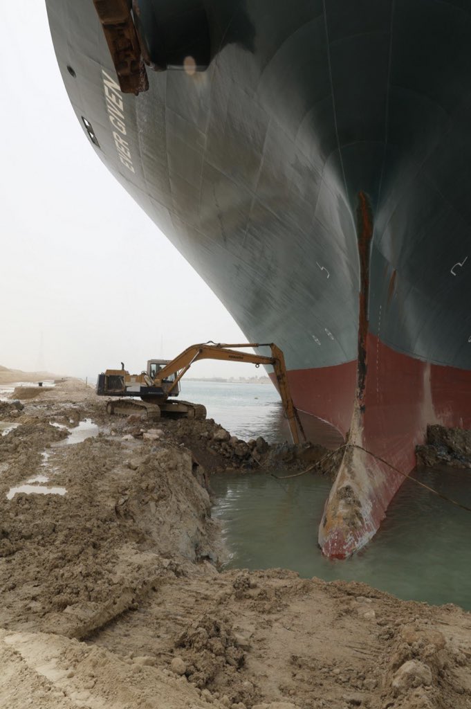 KrisFran123's tweet photo. It’s the ‘little excavator that could’.  No pressure here at all.  30% of global trade at a standstill.  No pressure.  Maybe it’s time to reconsider the size of these ships in our waterways?  #suezsituation https://t.co/NfqiEih9nw