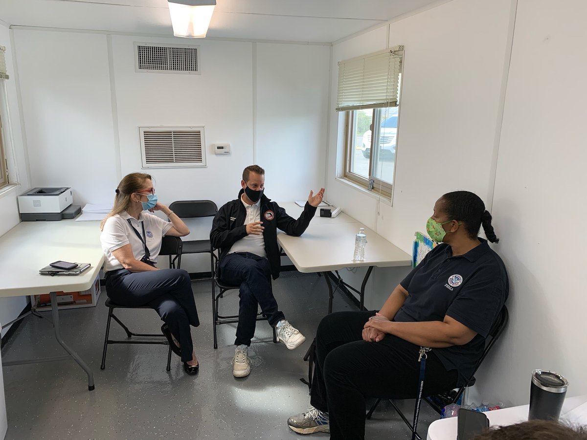 Three people sit in room facing each other. 