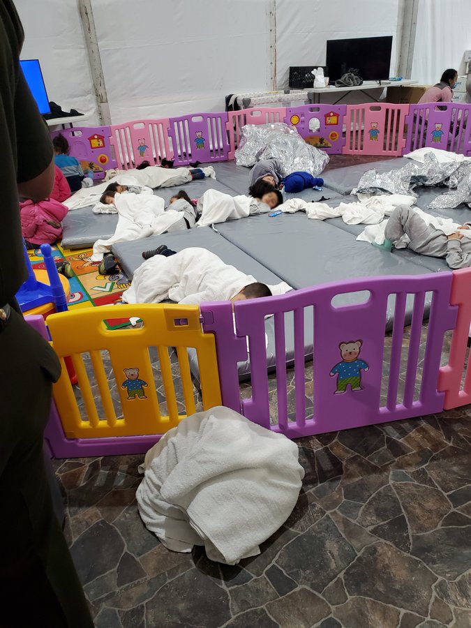 Children laying on the floor in a pinned off area. They have blankets and a gymnastic pad to lay on.  