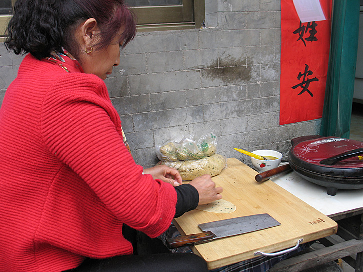 Susan_McKee's tweet photo. A food vendor plies her artistry in #Dangjia Village, just outside #Hancheng, #Shaanxi, #China, in 2018. It's like a step back in time, with 125 grey-brick courtyard houses, notable for their carvings and a mix of different architectural styles (mostly 14th C). #Asia #foodie https://t.co/IkuChT5MIv
