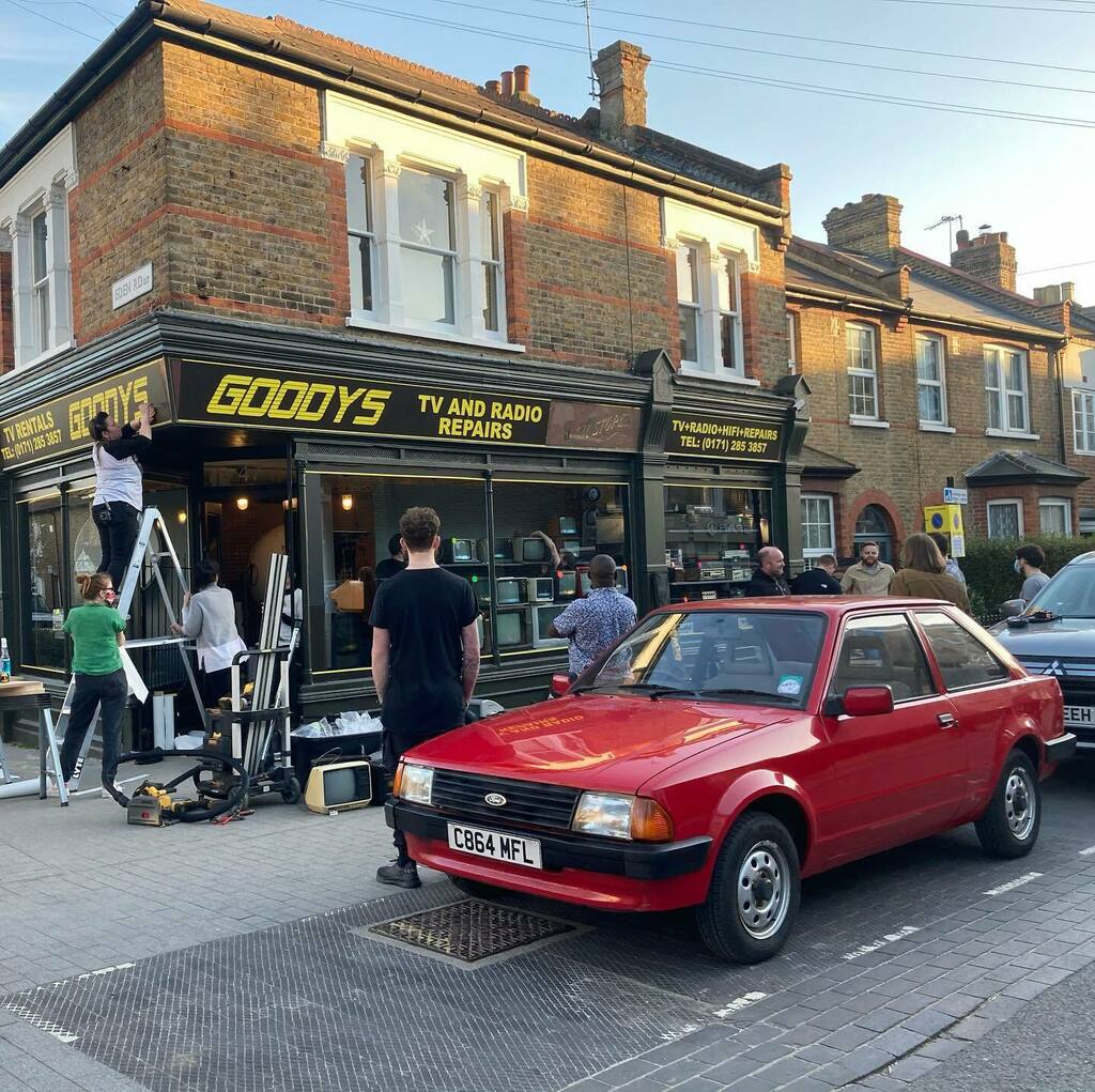 🎥 Film crew in the village transforming Ison’s shop front into an 80s TV and radio repair shop - complete with cars outside. 🎥