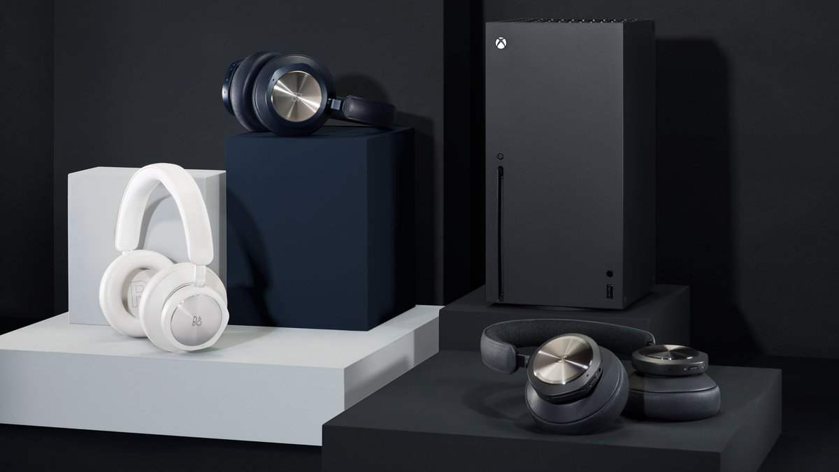The three new Beoplay Portal headsets from B&O are arranged on like colors from left to right: Grey Mist, Navy Brass, and Anthracite. An Xbox Series X stands in the background. 