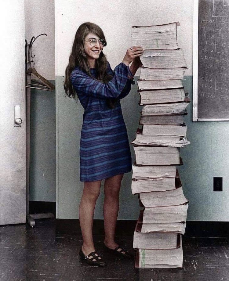 Margaret Hamilton standing next to the pile of codes she wrote that took the first humans to the moon