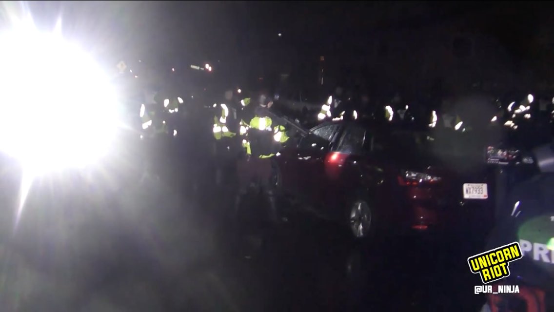 After several arrests as state patrol riot line advances, a trooper aims his munitions launcher directly at the driver or a vehicle that seemed to be trying to leave