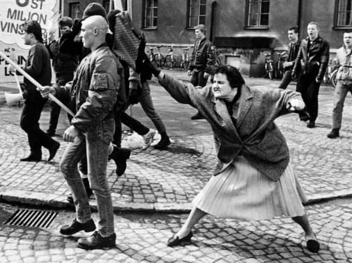 antifa_w's tweet photo. Heute vor 36 Jahren trat Danuta Danielsson, Tochter einer jüdisch-polnischen Holocaustüberlebenden, im schwedischen Växjö militant einer Neonazi-Demo entgegen. Dabei hat sie mit ihrer Tasche einen der Nazis vermöbelt. Die Szene wurde von einem Journalisten festgehalten. https://t.co/Xl3gzP50fY