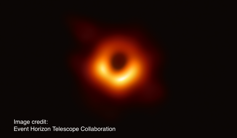 First image of a black hole, a blurry orange and yellow circle, heavier on the bottom, on a black background