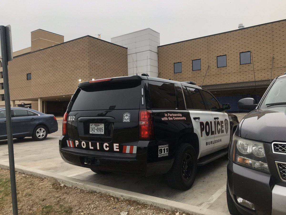JHowl04's tweet photo. At JPS, where a Burleson officer is being treated after he was shot multiple times during a traffic stop. Officers from different departments are standing outside the ER. There are police cars parked in the ambulance entrance. https://t.co/O120huZFPD