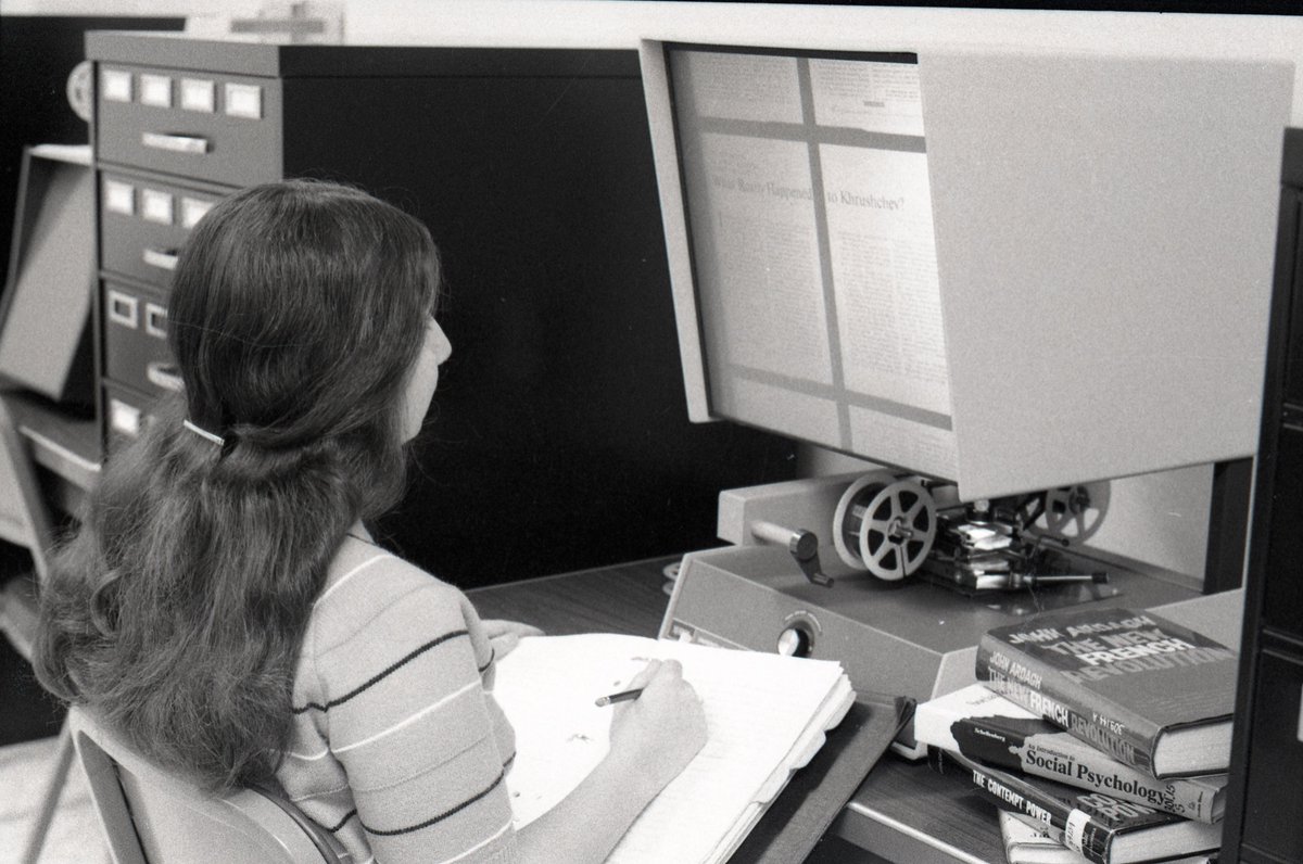 Photo of the week: In the spirit of National Library Week, a picture from the 1970s of a student doing research in the library the old fashioned way with paper books and microfiche to access newspaper articles. #Felician #library #NationalLibraryWeek