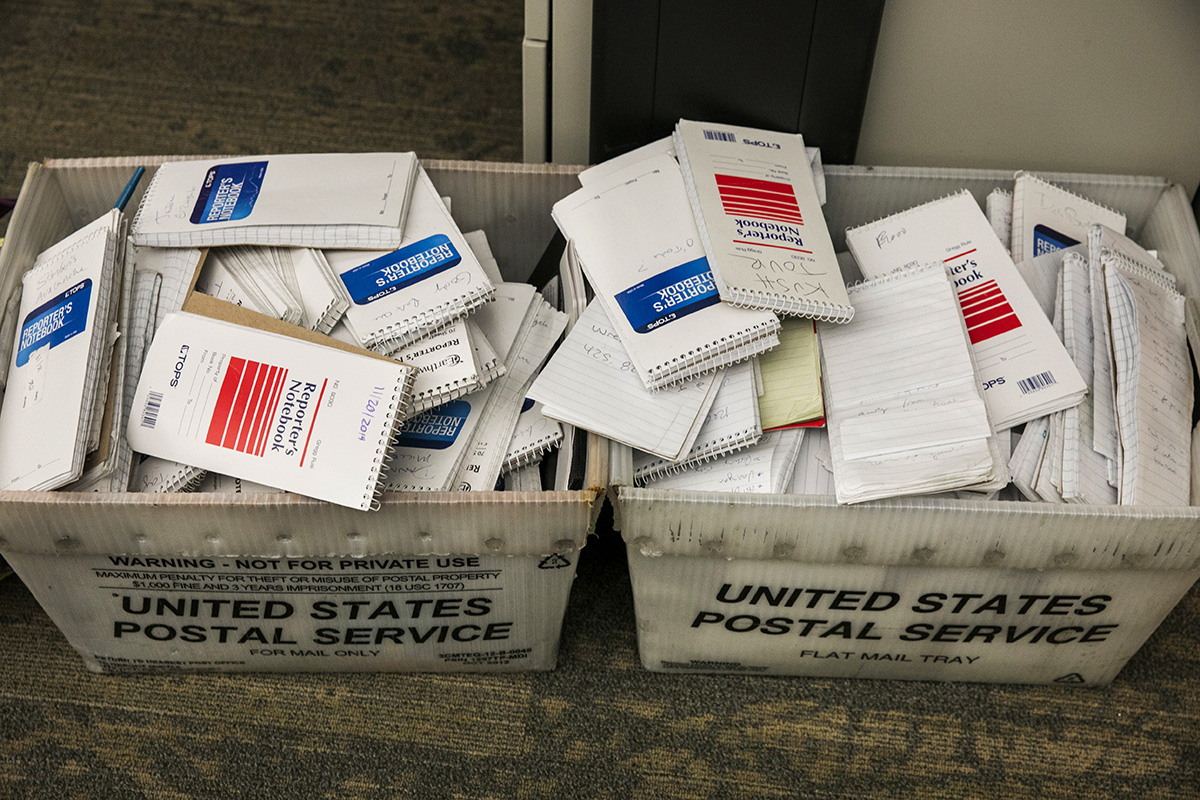 Photo of two USPS white bins overflowing with used reporter's notebooks