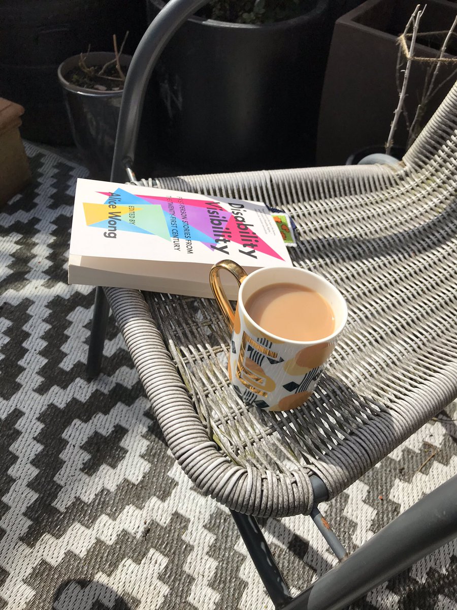 Taking advantage of the sunshine for a tea and read break. #BookTwitter #DisabilityVisibility #Tea [ID: a cup of tea and the Disability Visibility book sits on a garden chair. Pot plants are behind the chair.]