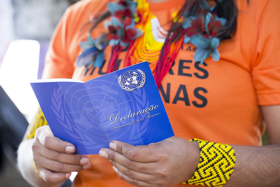 Detalhe: mulher lendo versão em portugués da Declaração Universal dos Direitos Humanos. Foto: ONU Brasil/Karina Zambrana