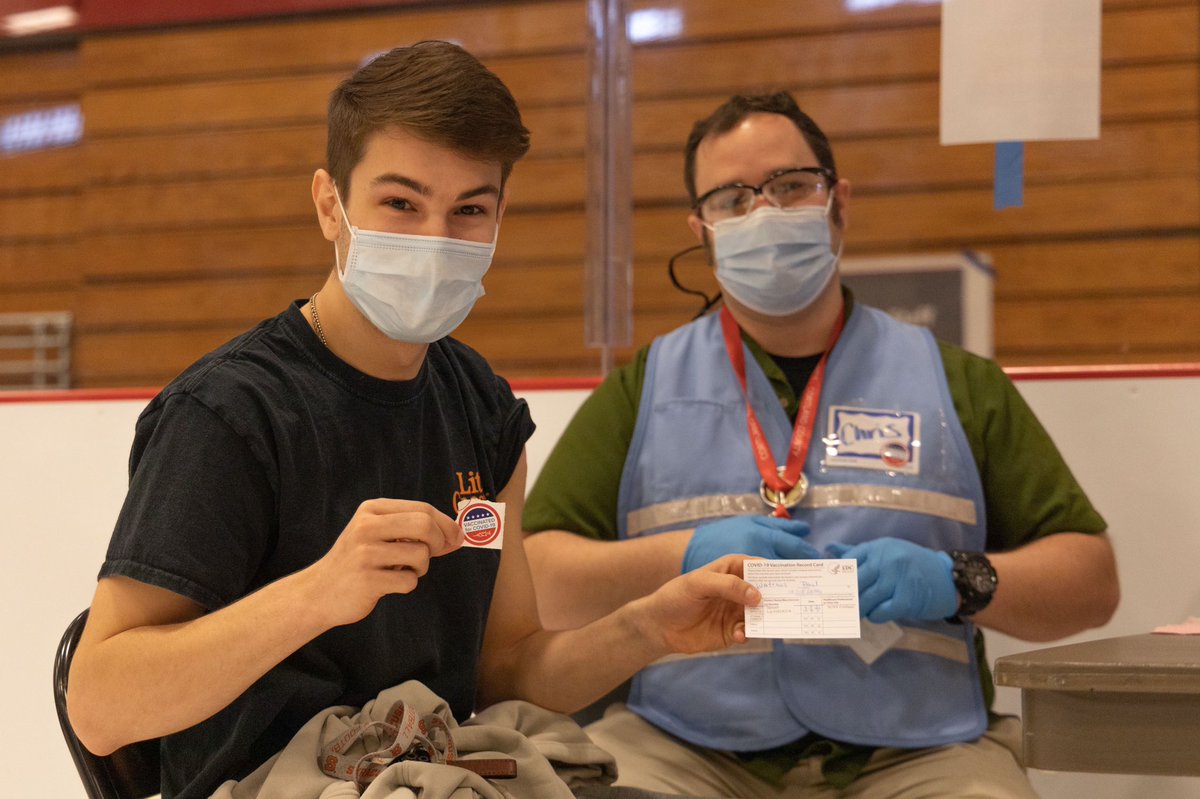 suny_cortland's tweet photo. Sophomore exercise science major Paul Watrous from Homer, N.Y. (holding a sticker) was first in line at today’s COVID-19 vaccine clinic at Alumni Arena. #RedDragonSafe https://t.co/UVytdDHspB