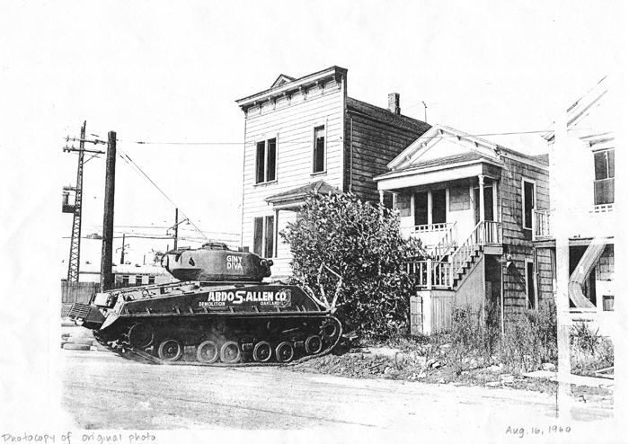 This is a picture of a tank demolishing homes in West Oakland to make way for 980, 880, BART, the Post Office, parking lots or any of the many urban renewal projects occurring at the time.