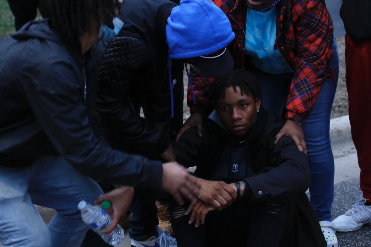 One of Wright’s friends sits in the street, appearing to be in shock, comforted by friends and demonstrators as he has trouble standing back up