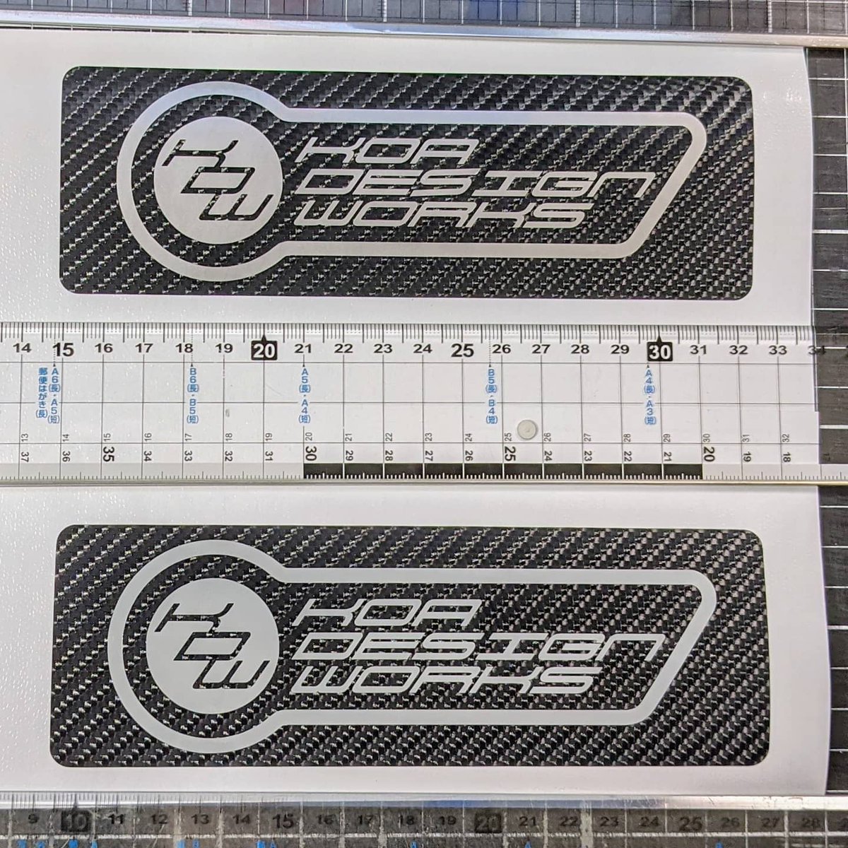 KOA7177's tweet photo. 汎用ナンバーガードのベースが一部丸見えの状態なので、なにか貼ることに
ステッカー作成の時に使ってる屋号【KOADESIGNWORKS】の新デザイン2パターン作成
下側を採用
カーボンシートをベースにして貼り付け予定
#koadesignworks
#ステッカー
#デザイン https://t.co/Qo1IP6RVJ0