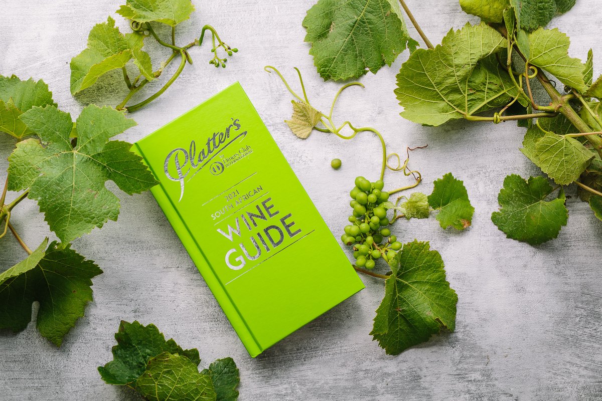 The 2021 Platter's Wine Guide with its apple green cover, placed on a grey background and surrounded by wine leaves