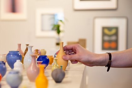 A hand picking up a handmade ceramic vase
