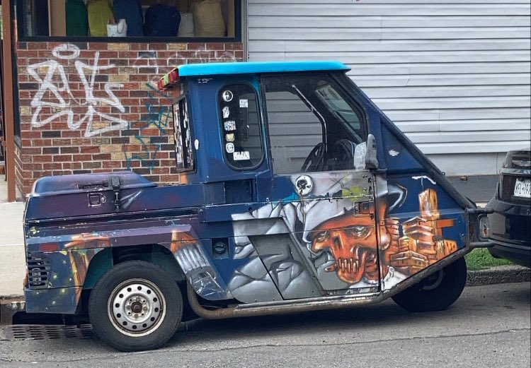 a weird little car with a weird little mural on it