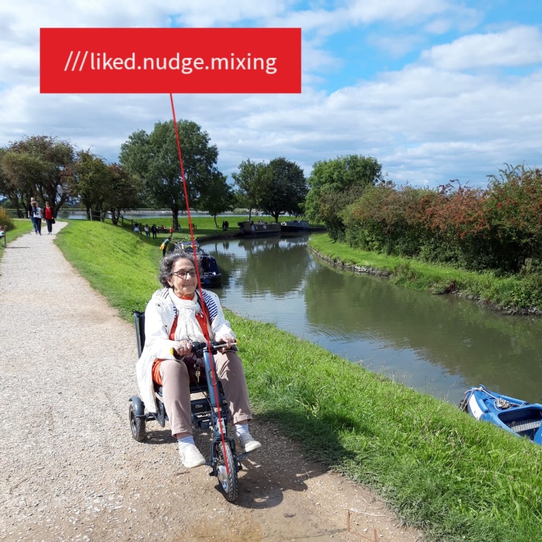 A photo of Glynnis on her mobility scooter on a path near a canal at what3words ///liked.nudge.mixing