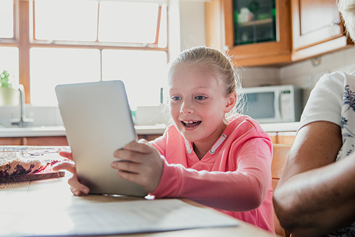 middle grade student using tablet in home kitchen