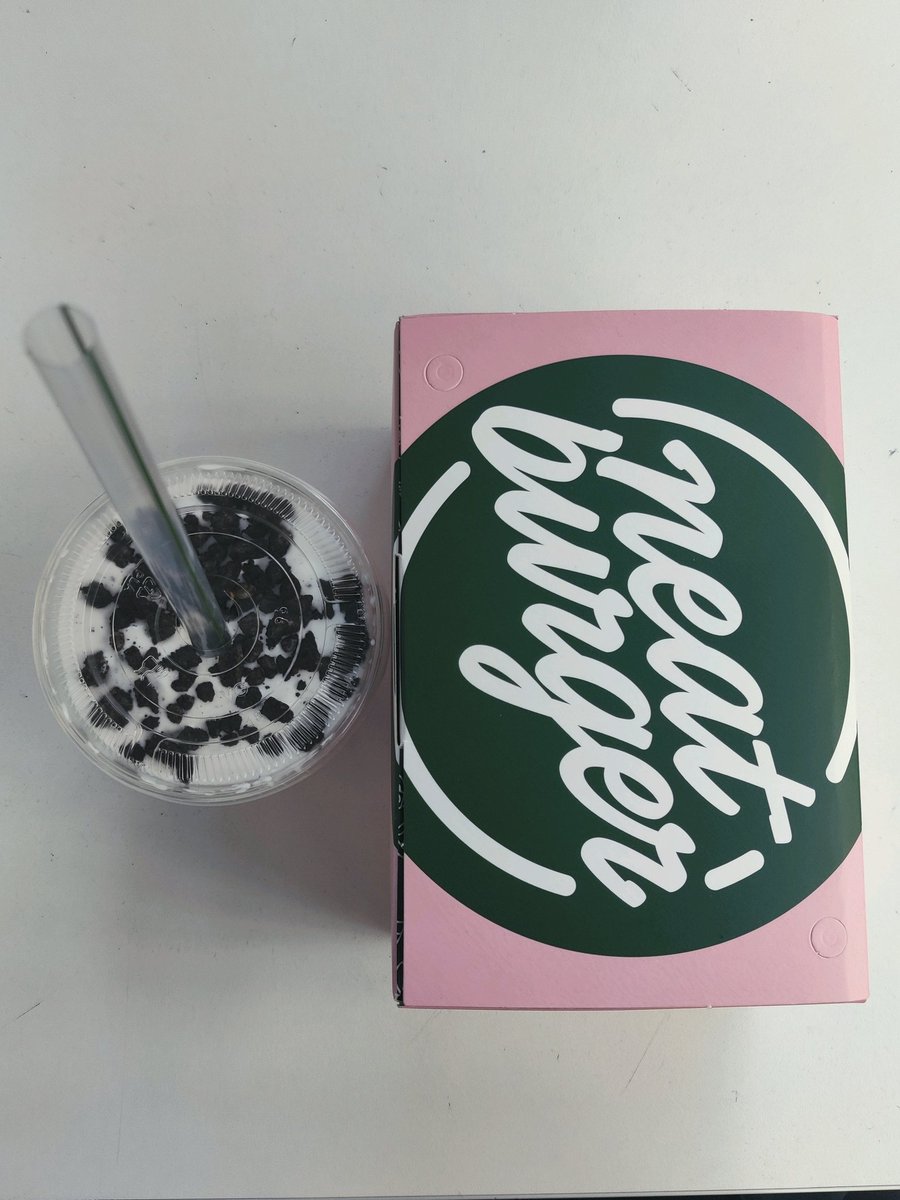 Flat lay image of a pink and green burger box with branding "Neat Burger" on alongside a milkshake drink.