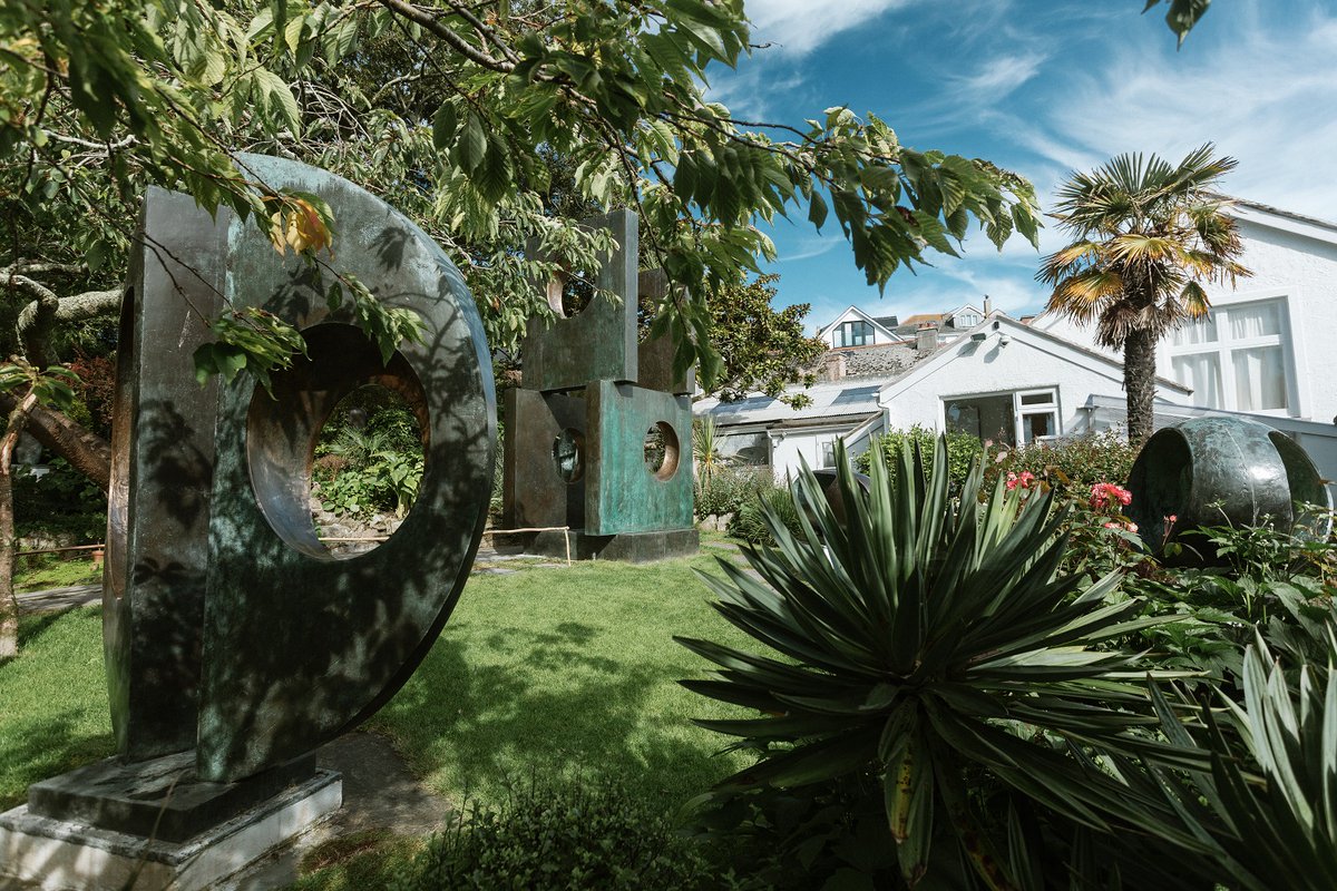 Barbara Hepworth's Sculpture Garden, with a view of three sculptures, trees, plants and blue skies
