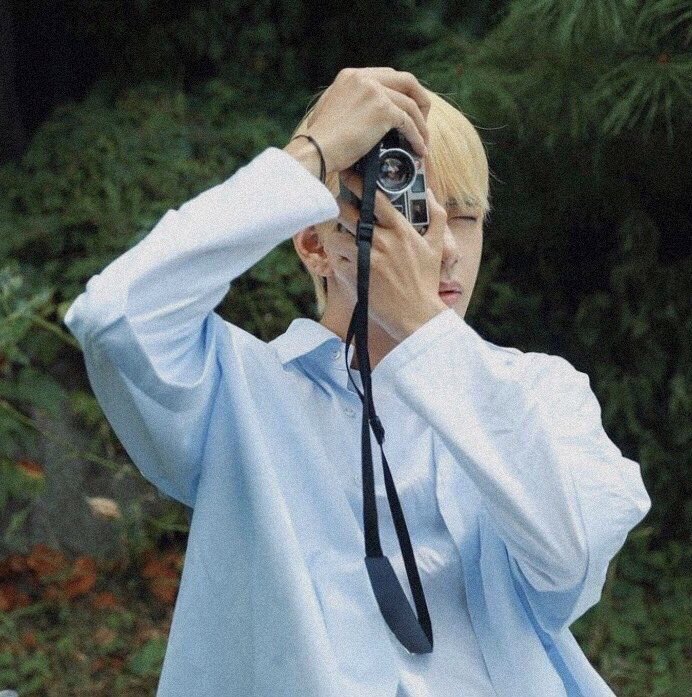 taehyung walking around the street with his camera, looking for places to take photos