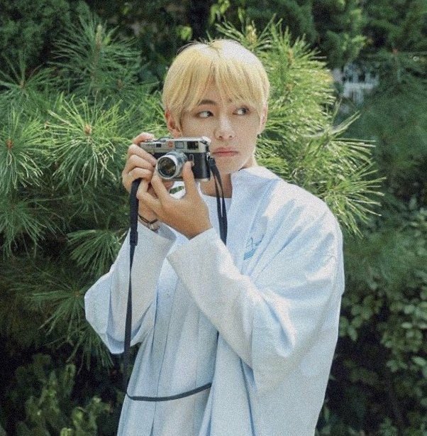 taehyung walking around the street with his camera, looking for places to take photos