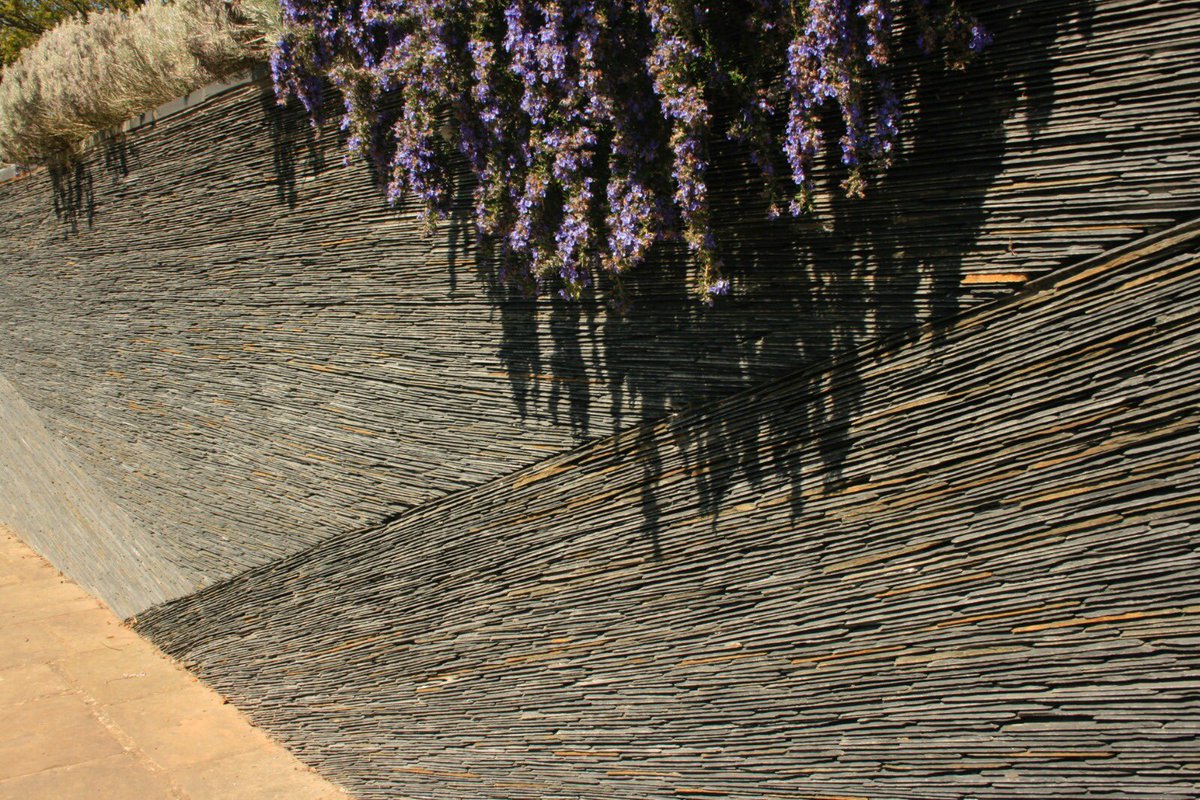 Over 500 m yr old, Welsh slate is acknowledged as the finest of its type worldwide; light grey in colour with a subtle reflective surface, the riven cut edge lends a chalky white slant to the grey &amp; the material used in the artwork is a waste product from the roof tiling industry