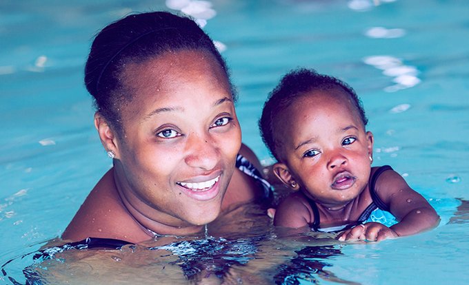 A mother in a pool with her young child.