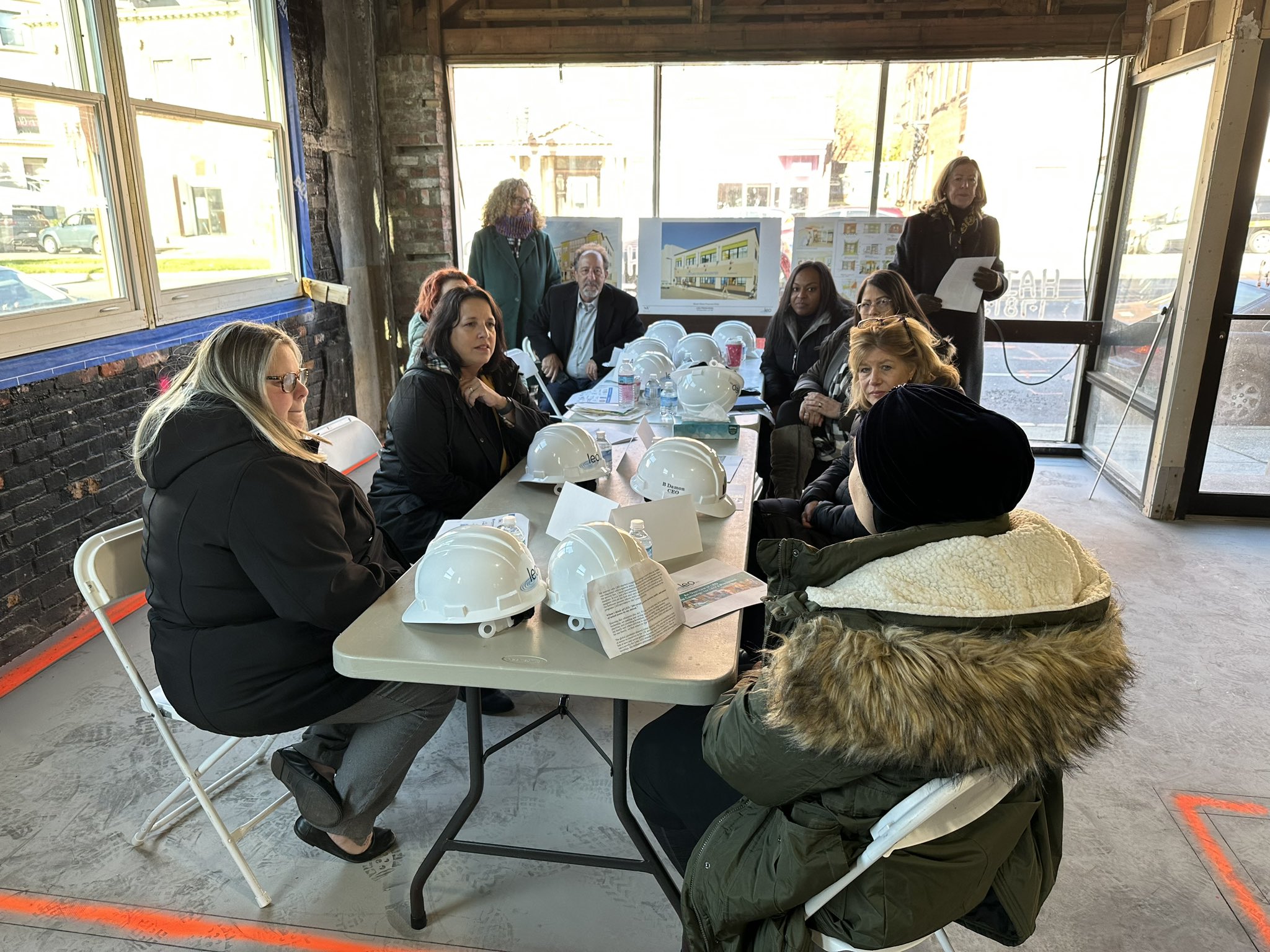 LG Driscoll at table of people inside building under construction.