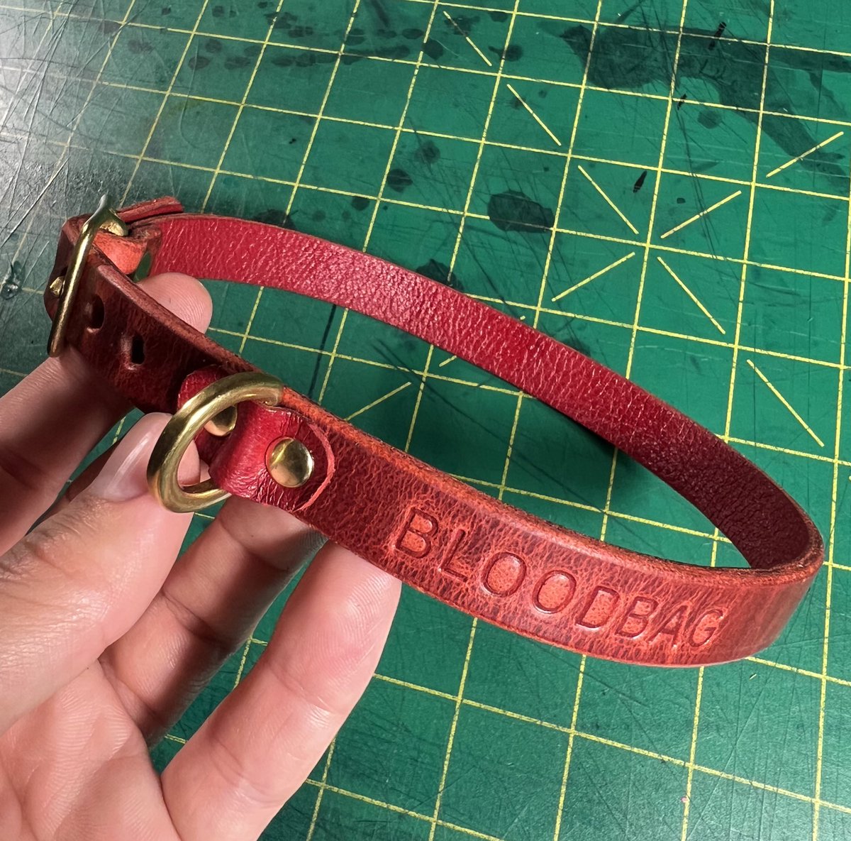 A red &amp; brass collar lined with soft moto leather and stamped with the word BLOODBAG