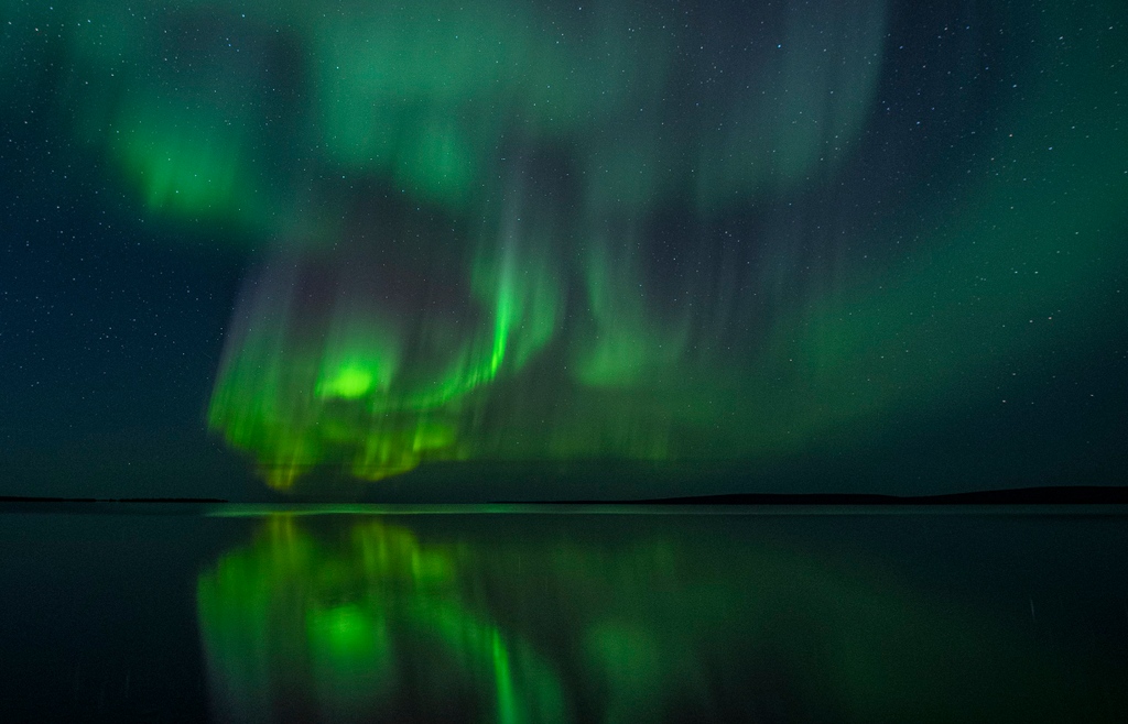 Step into a mesmerizing dreamscape as the skies of Northwest Territories, Canada ignite with the ethereal beauty of the aurora. Mother Nature's celestial ballet in captivating hues of vibrant colors. Prepare to be spellbound by this magical reflection of awe-inspiring wonder!