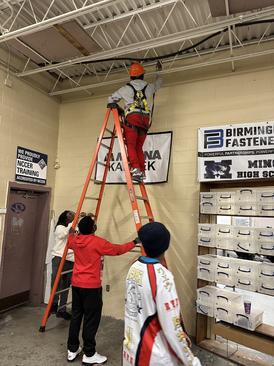 MHSIndMain's tweet image. Using what we learned in class to hang another sponsor banner in the shop. Proper PPE doning; hard hats, safety harness and lanyards used, all while practicing proper ladder safety and procedures. @MinorHighTigers @JEFCOCareerTech @SkillsUSA