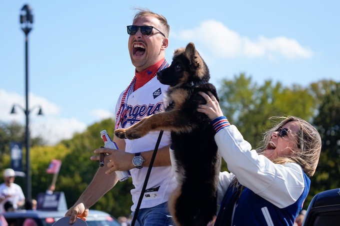 Nathaniel Lowe yells to fans during the World Series Championship parade as a dog is held up next to him.