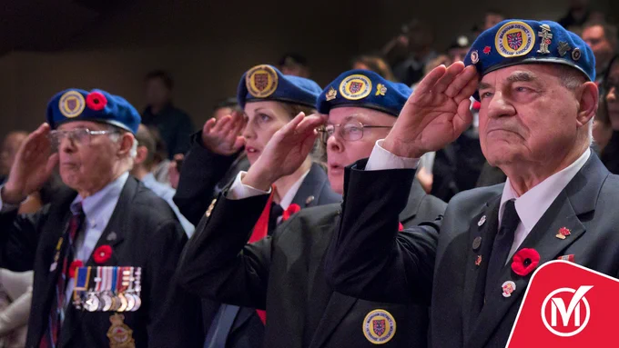 Four veterans saluting while wearing poppy pins.